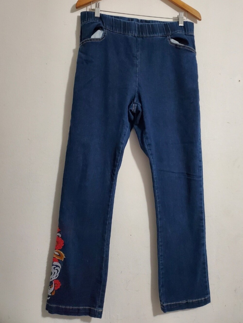 Blue jeans feature a comfortable pull-on floral embroidery on the lower leg